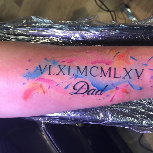 Ein Tattoo auf dem Arm einer Person mit der Aufschrift vi.xi.mcmlxv dad