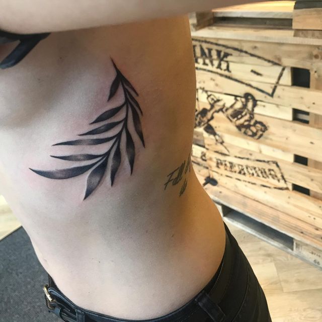 Eine Frau hat ein Blatttattoo auf ihrer Seite