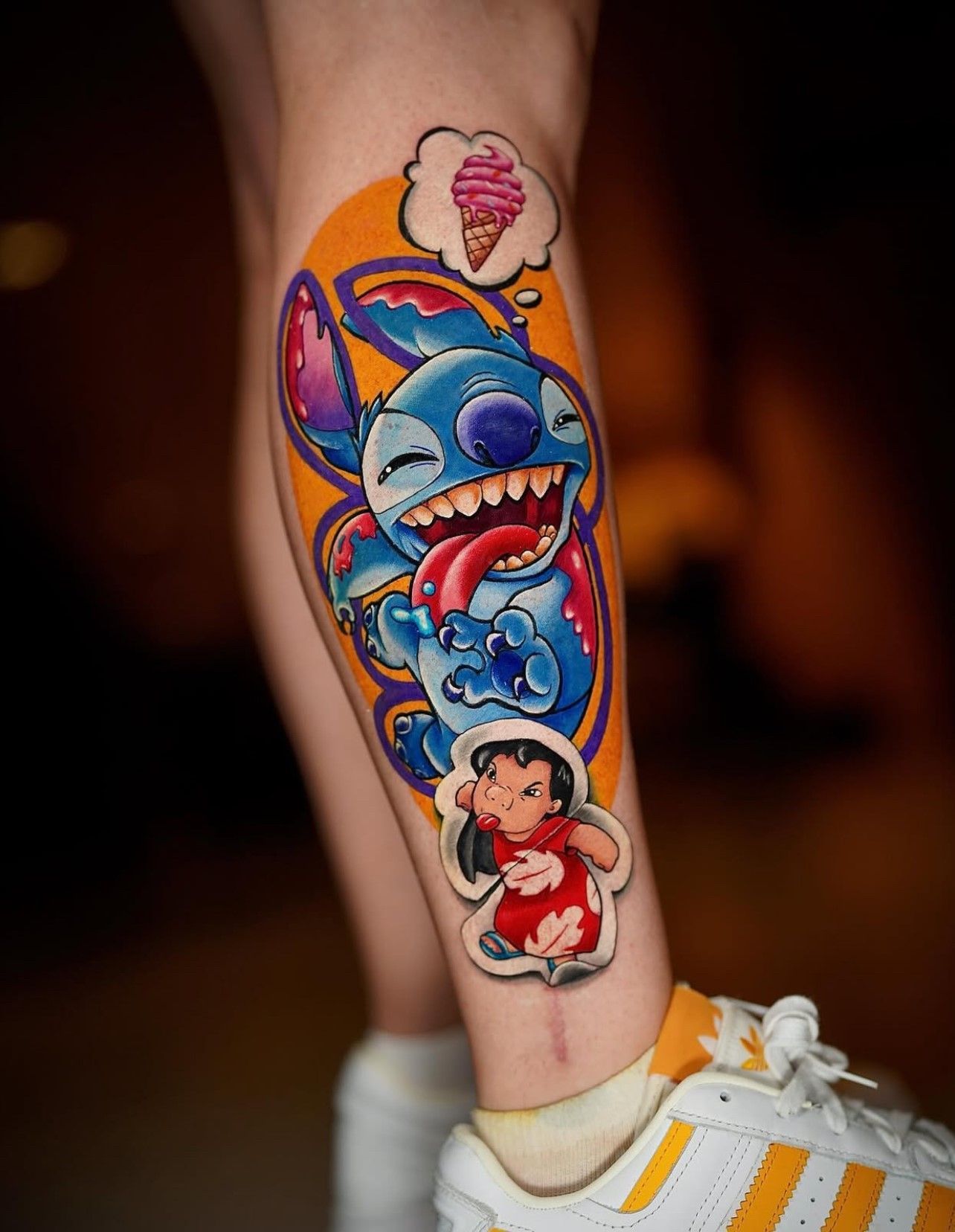 Eine Person hat ein Stitch- und Lilo-Tattoo auf dem Bein.