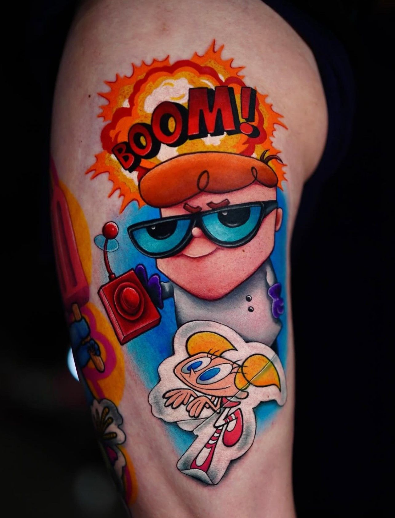 Eine Person hat eine Tätowierung von Dexter aus Dexter's Laboratory auf dem Arm.