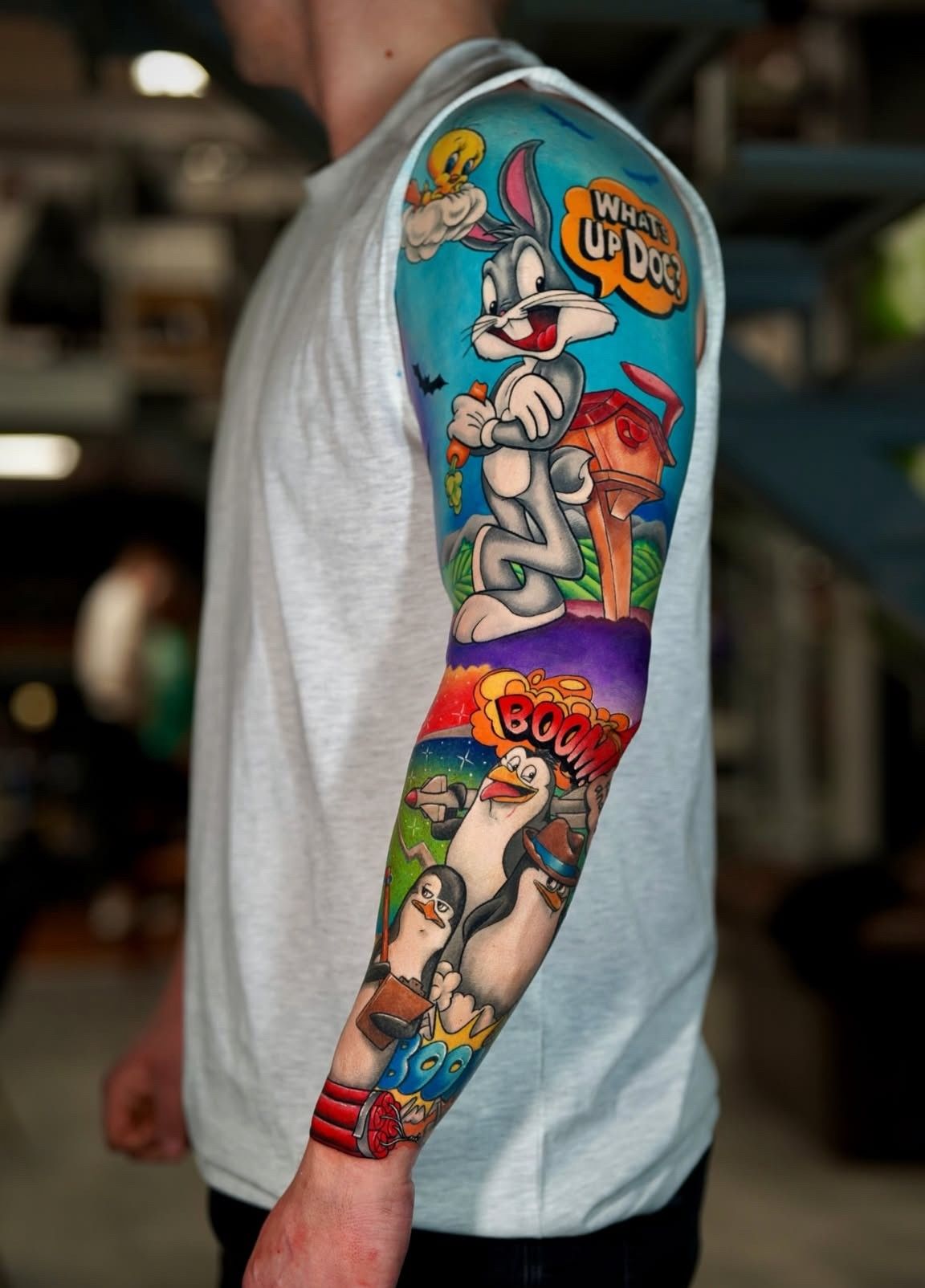 Ein Mann hat ein Ganzkörpertattoo mit Comicfiguren auf seinem Arm.