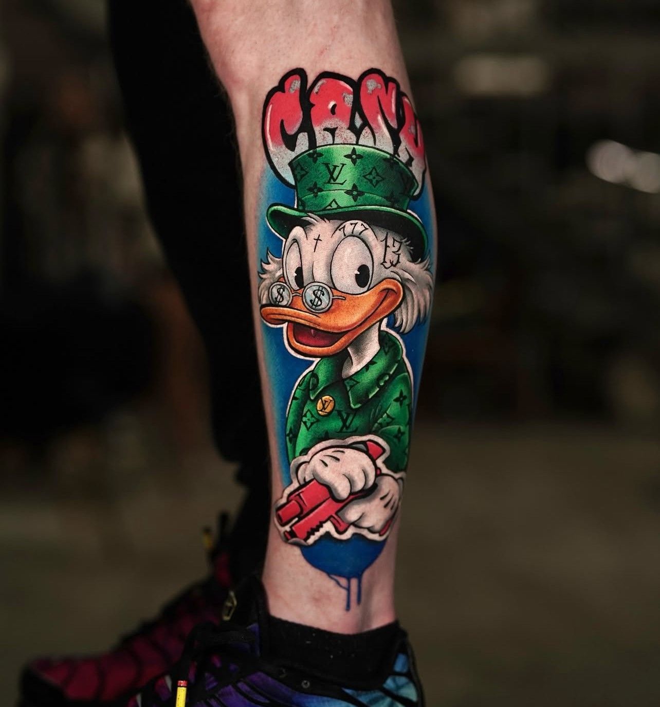 Eine Person hat eine Tätowierung von Mr. Duck auf ihrem Bein.