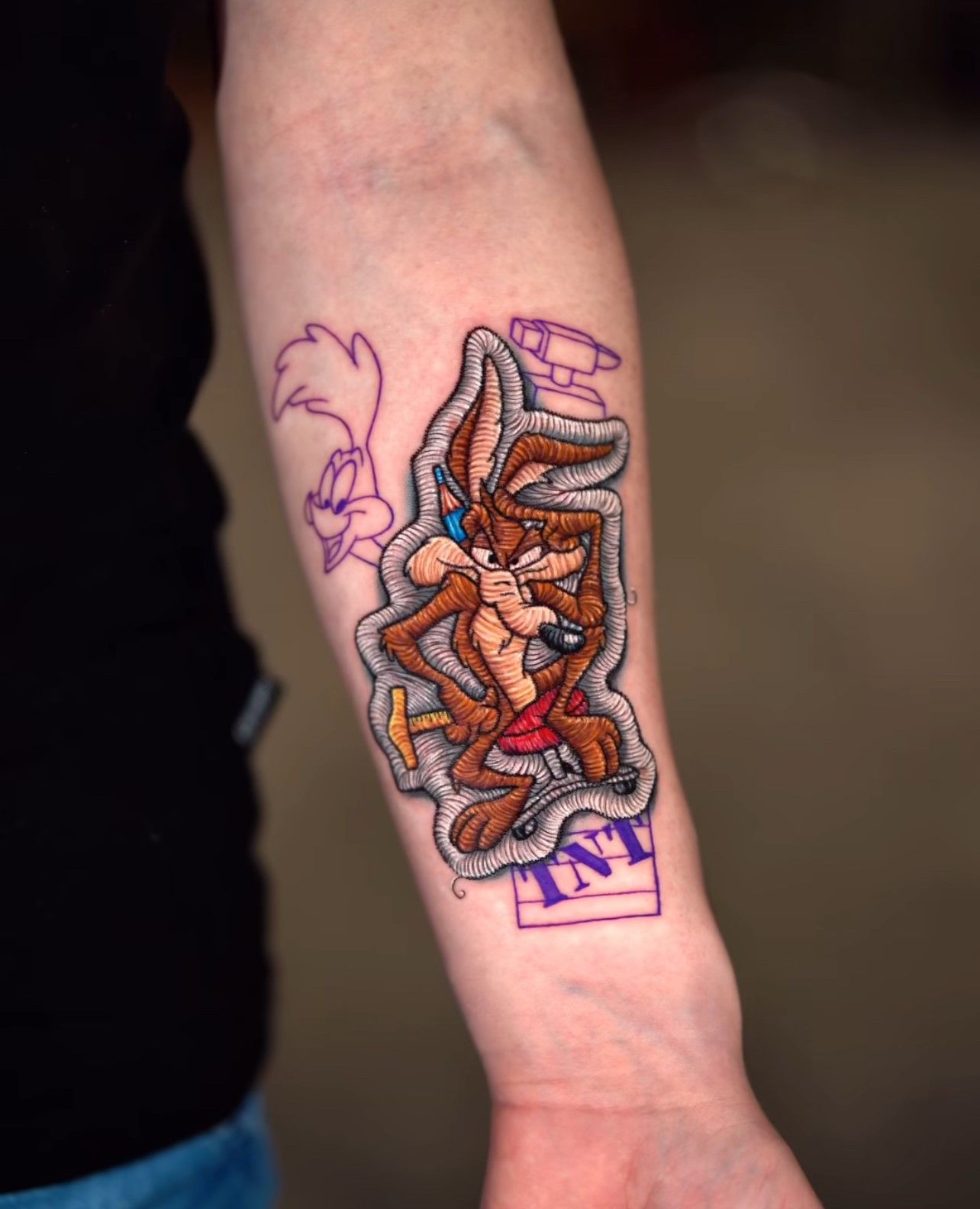 Eine Person hat eine Tätowierung eines Kojoten auf ihrem Unterarm