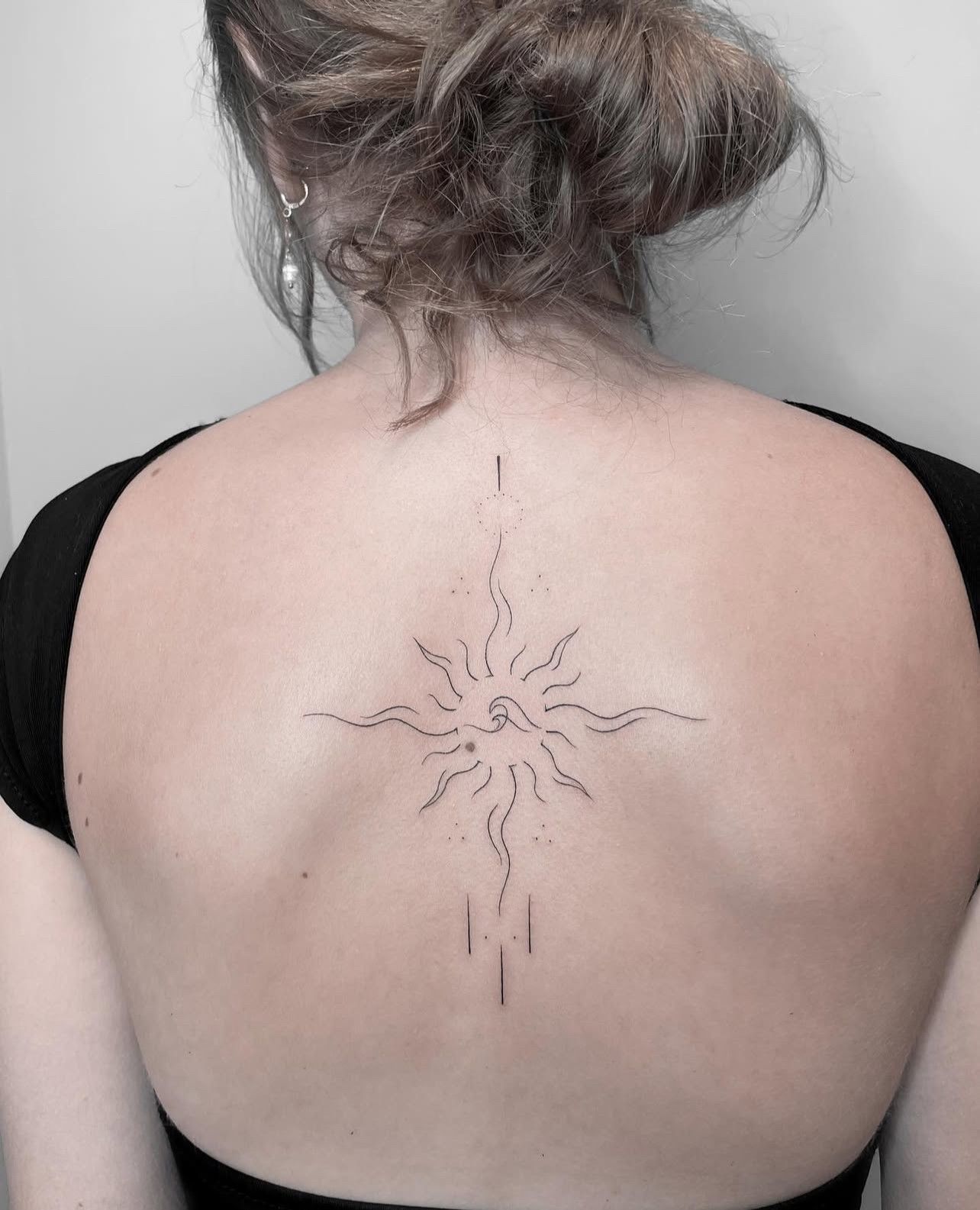 Eine Frau hat ein Tattoo auf dem Rücken, das wie eine Sonne aussieht