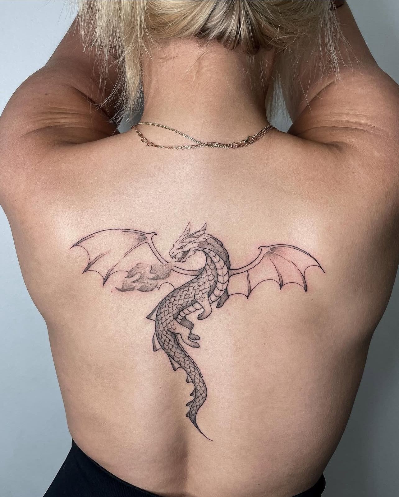 Eine Frau hat ein Drachentattoo auf ihrem Rücken.