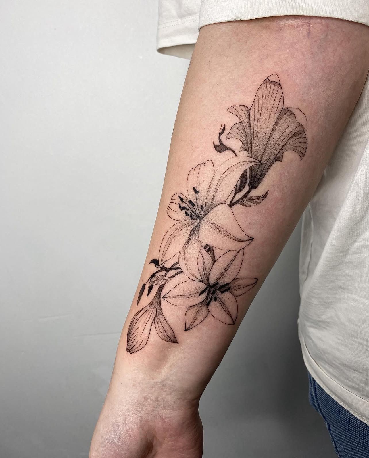 Eine Frau hat eine schwarz-weiße Blumentätowierung auf ihrem Unterarm.