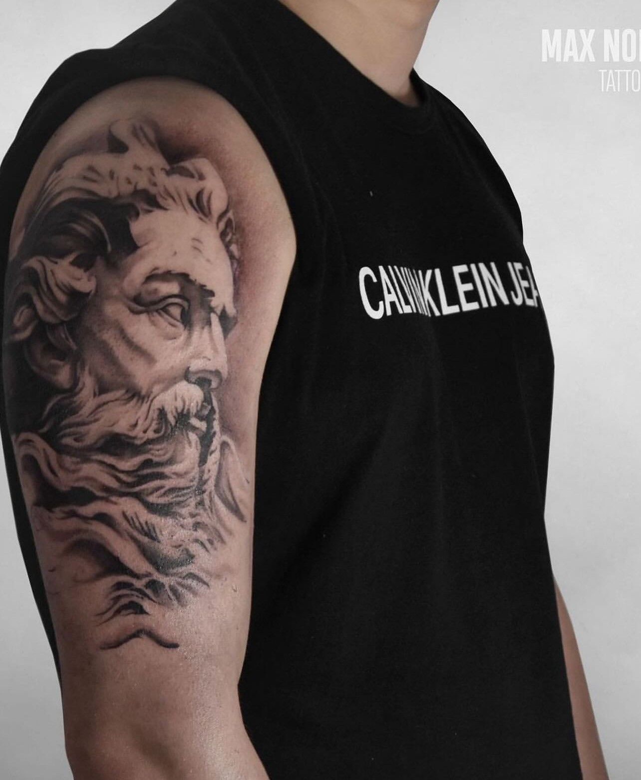 Ein Mann hat ein Tattoo auf seinem Arm, auf dem steht: Calvin Klein