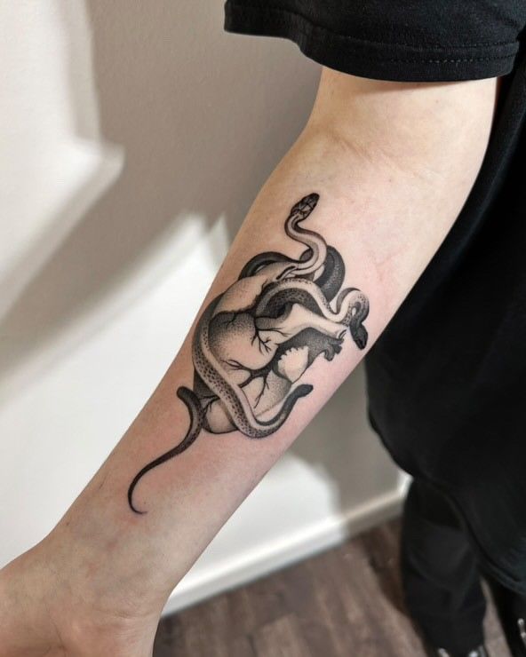 Eine Person hat eine Tätowierung einer Schlange, die um ein Herz gewickelt ist