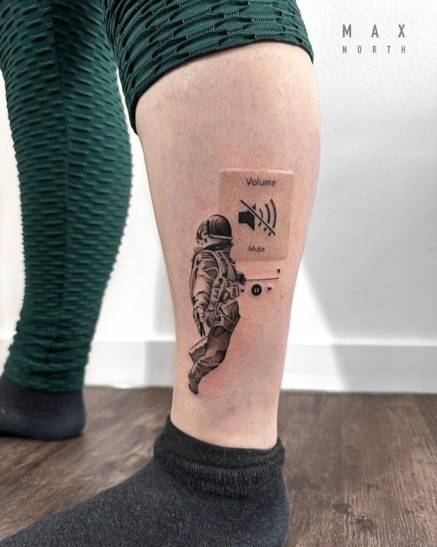 Eine Person hat ein Tattoo eines Astronauten auf ihrem Bein