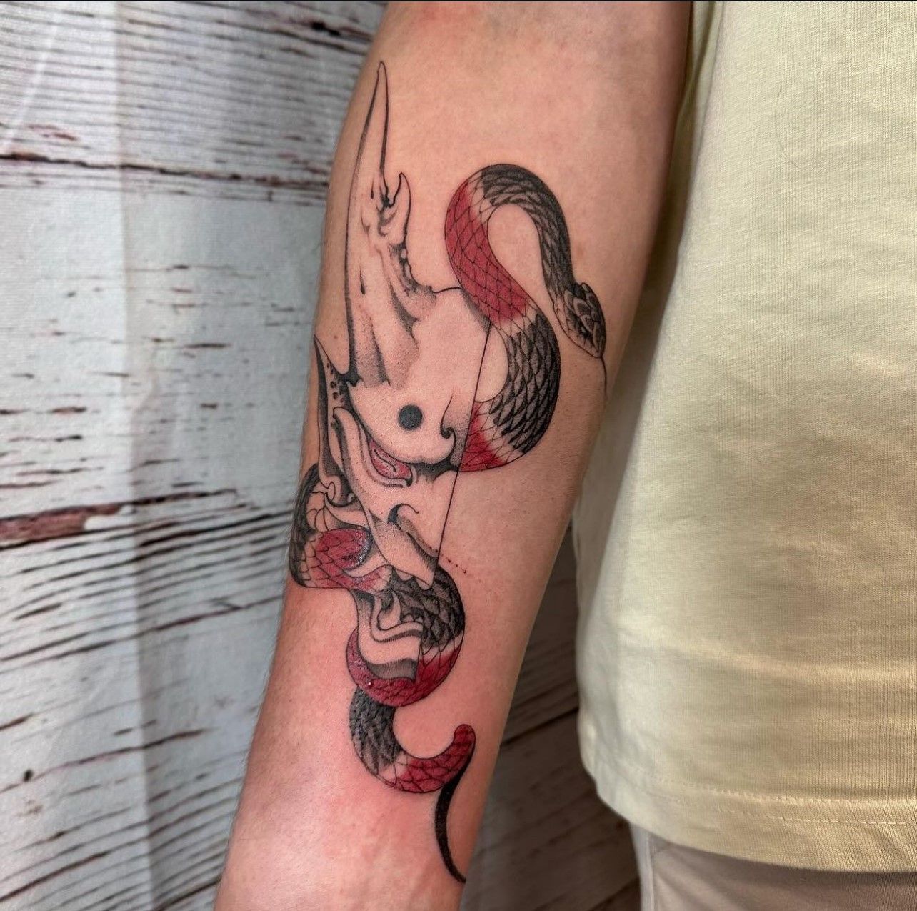 Eine Person hat eine Schlangentätowierung auf dem Arm