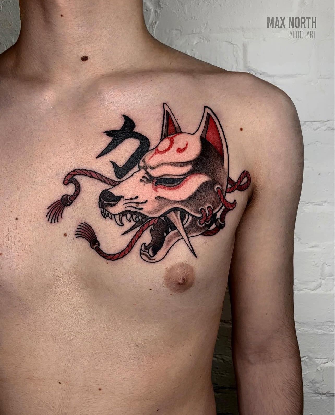 Ein Mann hat eine Tätowierung einer Fuchsmaske auf seiner Brust.