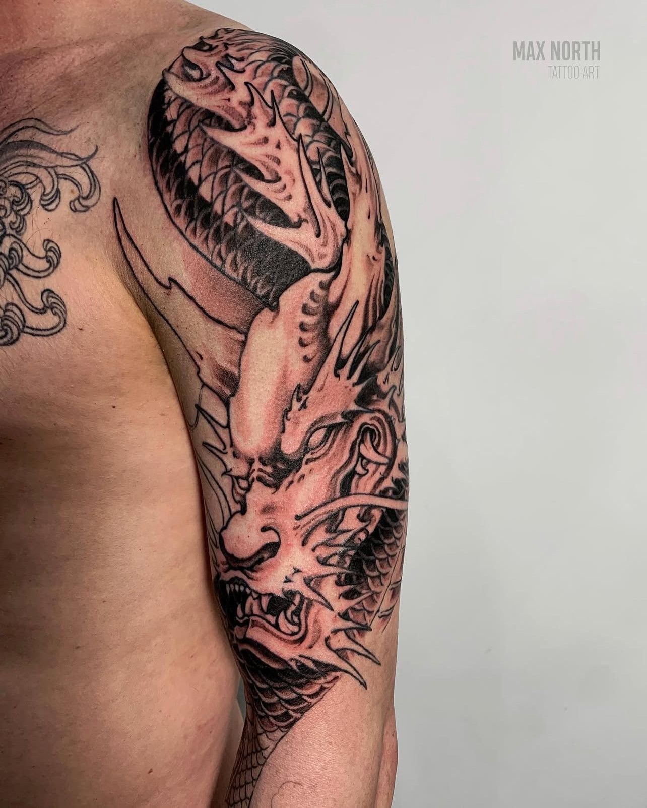 Ein Mann hat eine Drachentätowierung auf seiner Schulter.