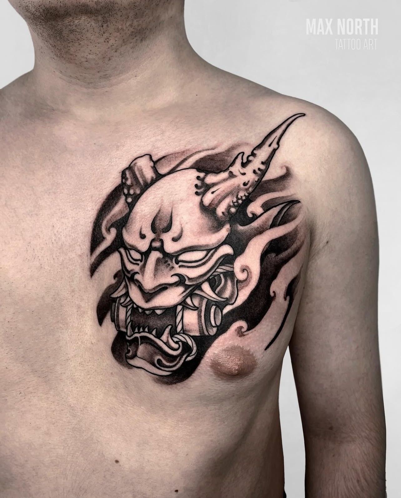 Ein Mann hat eine Dämonentätowierung auf seiner Brust.