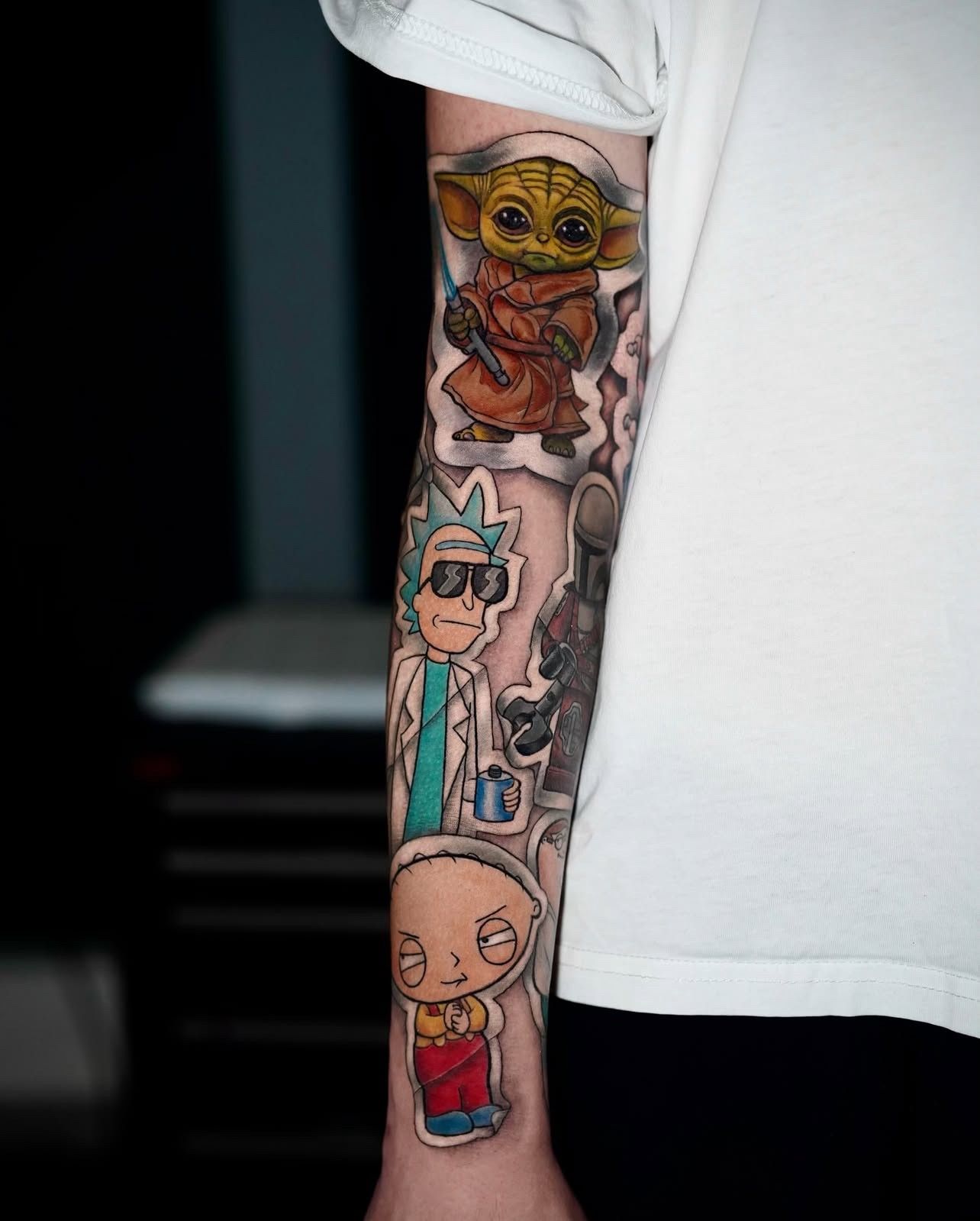 Eine Person hat ein Tattoo von Rick and Morty, Star Wars und Stewie auf dem Unterarm.