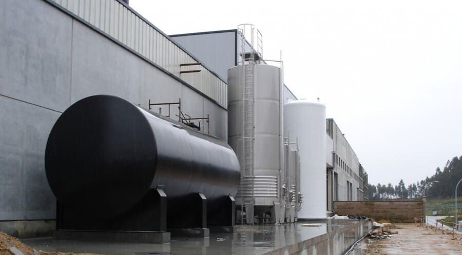 Un gran tanque negro está estacionado afuera de un edificio.