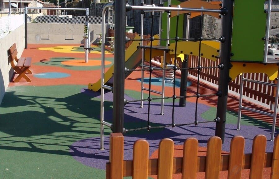 Un parque infantil con una valla de madera y un banco al fondo.