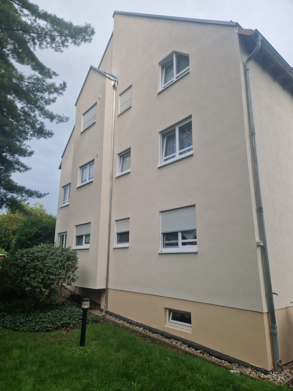 Mehrfamilienhaus mit heller Fassade und moderner Dachgestaltung