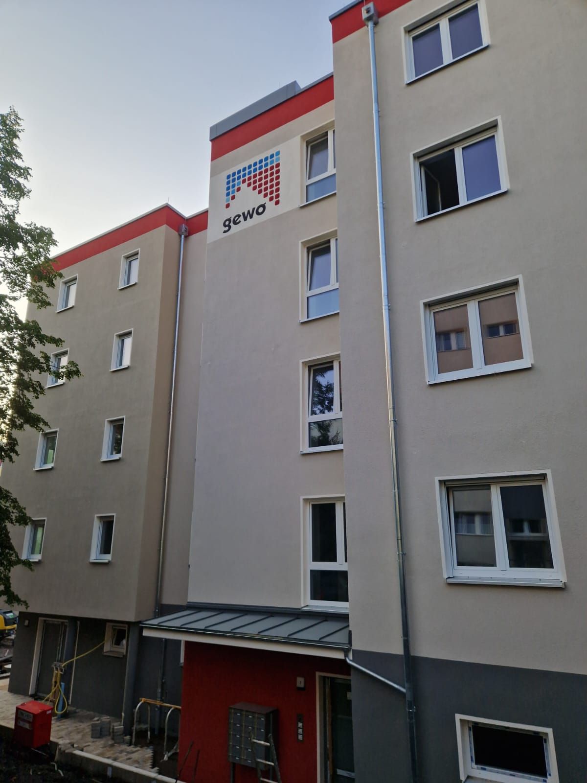 Sanierter Wohnblock in Freital mit Logo und heller Außenfassade