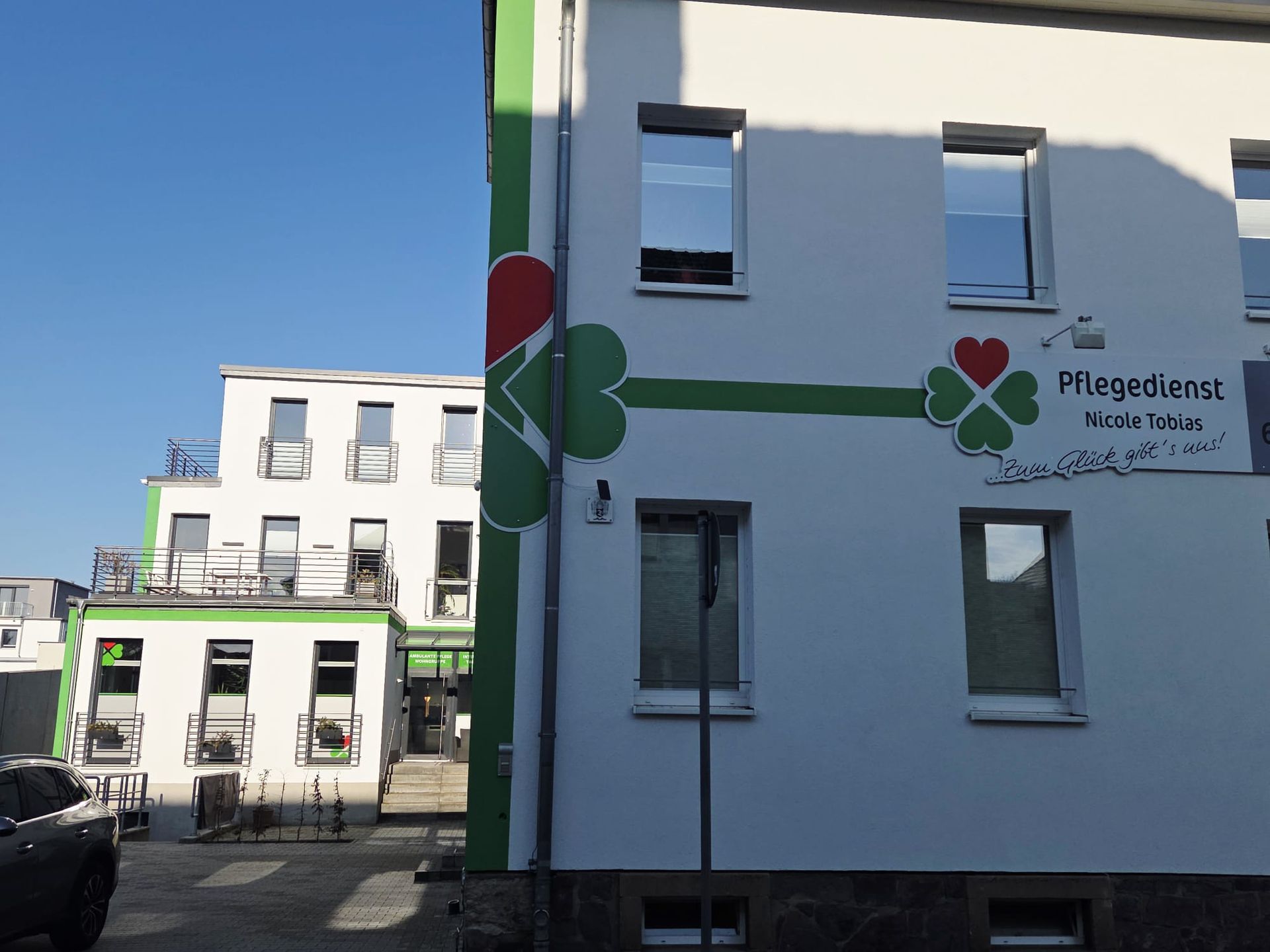 Gebäudeeingang eines Pflegedienstes mit Logo und moderner Architektur