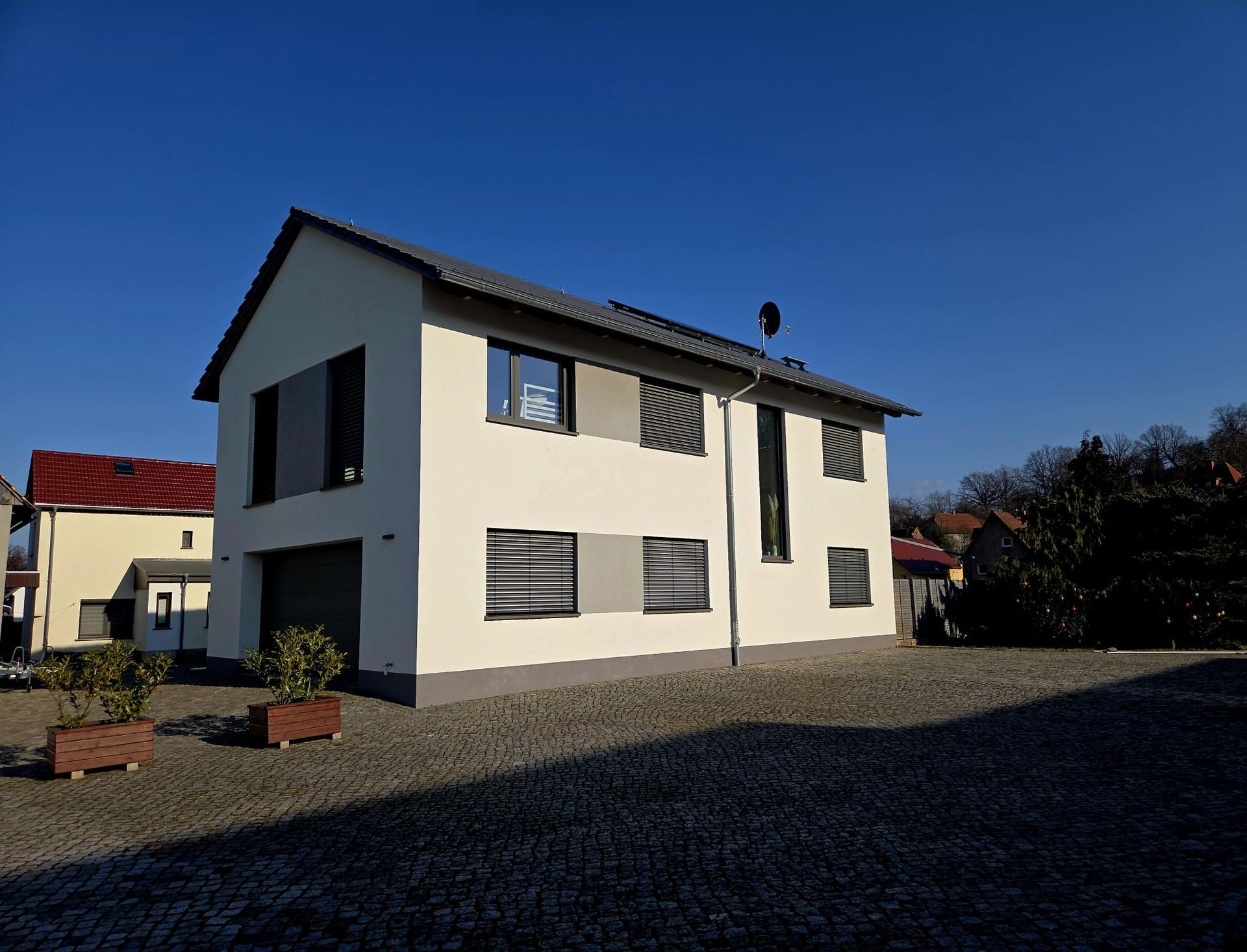 Modernes Wohnhaus mit klarer Linienführung und gepflastertem Hof