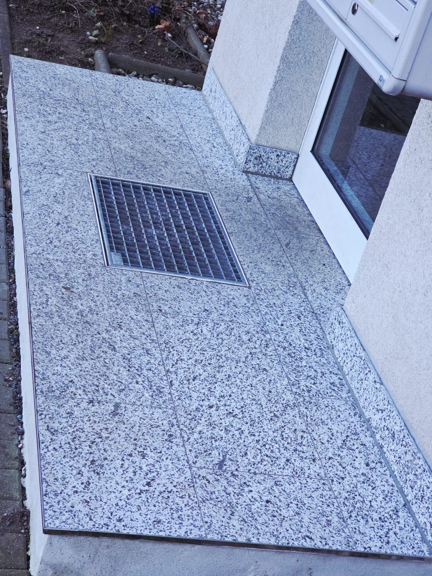 Detailaufnahme eines Eingangsbereichs mit Granitboden und Lüftungsgitter