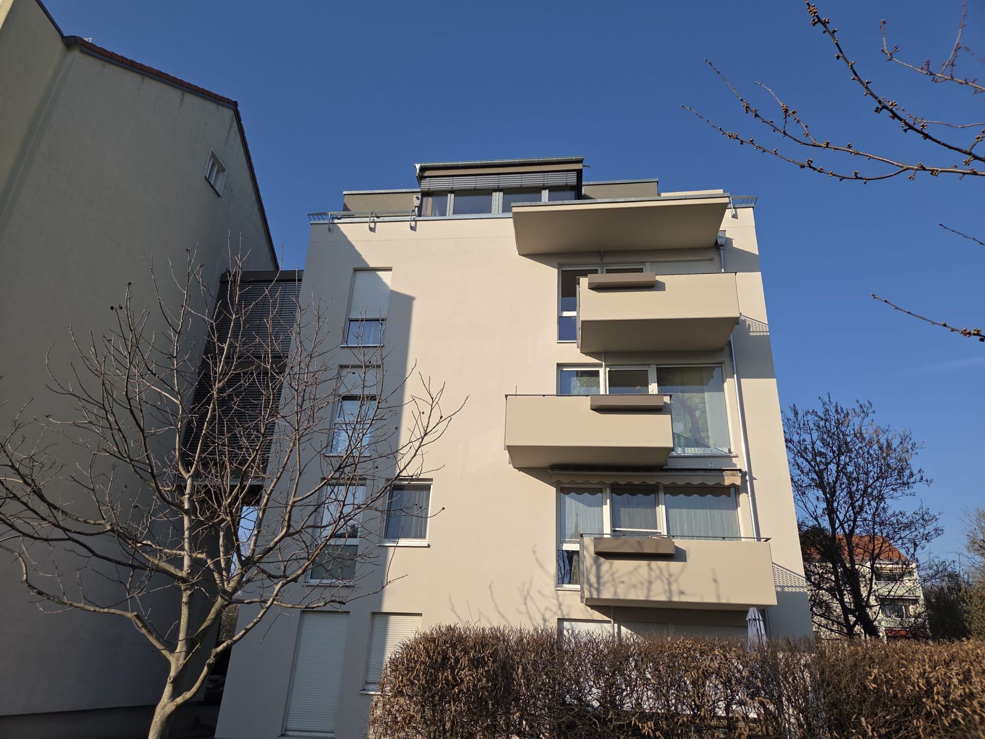 Modernes Wohngebäude mit Balkonen und heller Fassade unter blauem Himmel