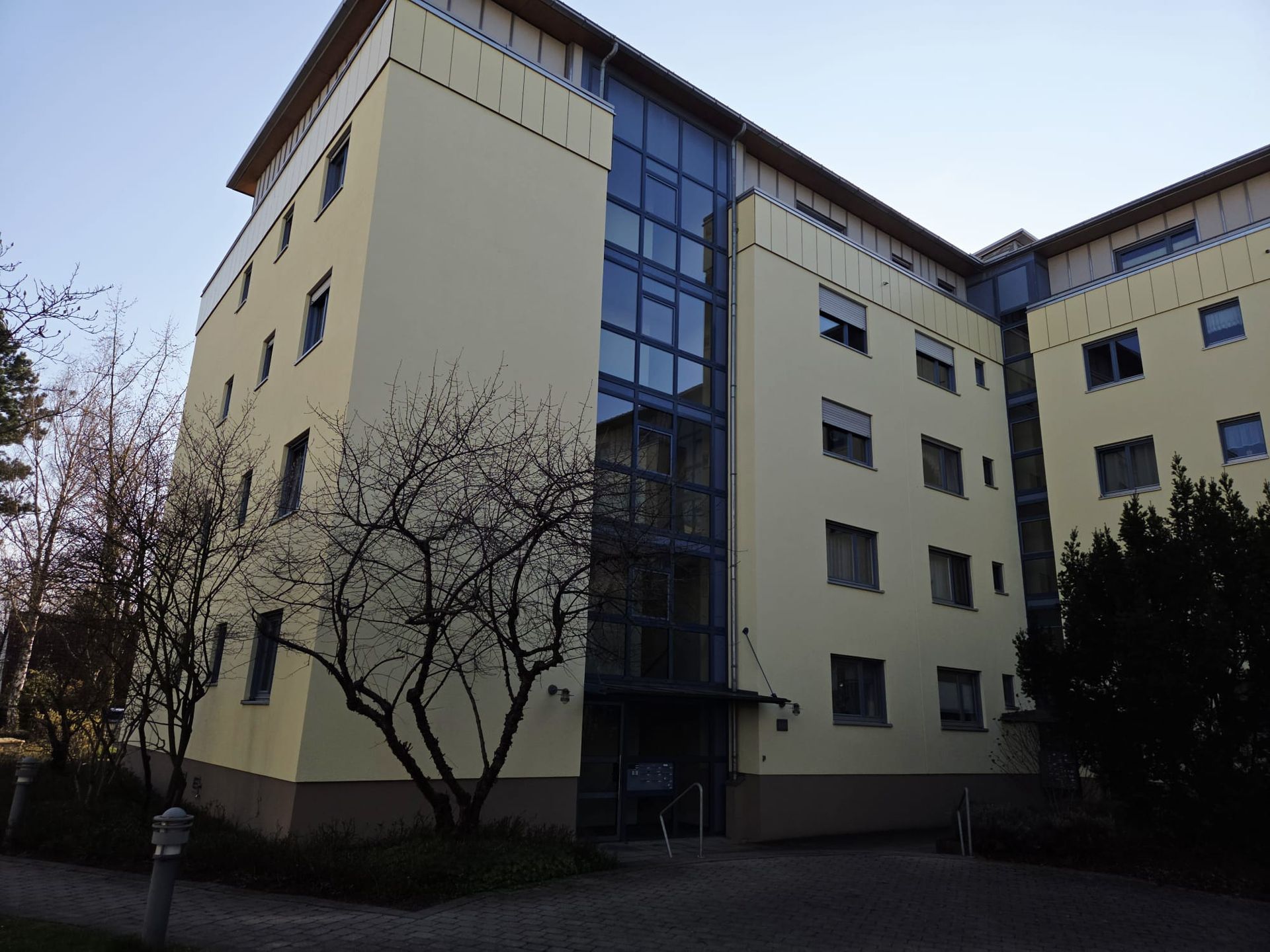 Mehrstöckiges Wohngebäude mit heller Fassade und großem Treppenhausfenster