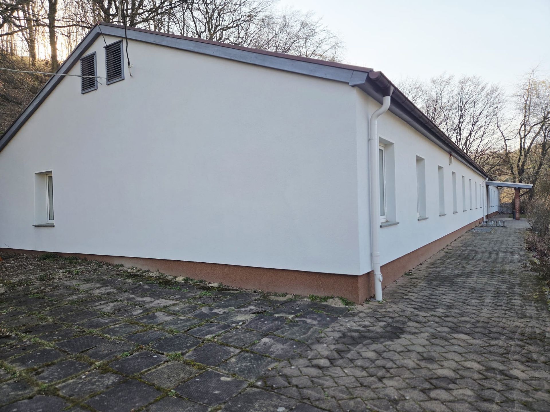 Eingeschossiges Gebäude mit heller Fassade und gepflastertem Weg in ruhiger Lage