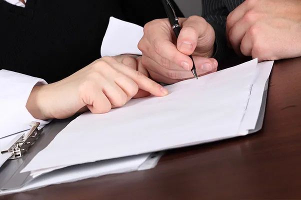 Un hombre y una mujer están firmando un documento con un bolígrafo.