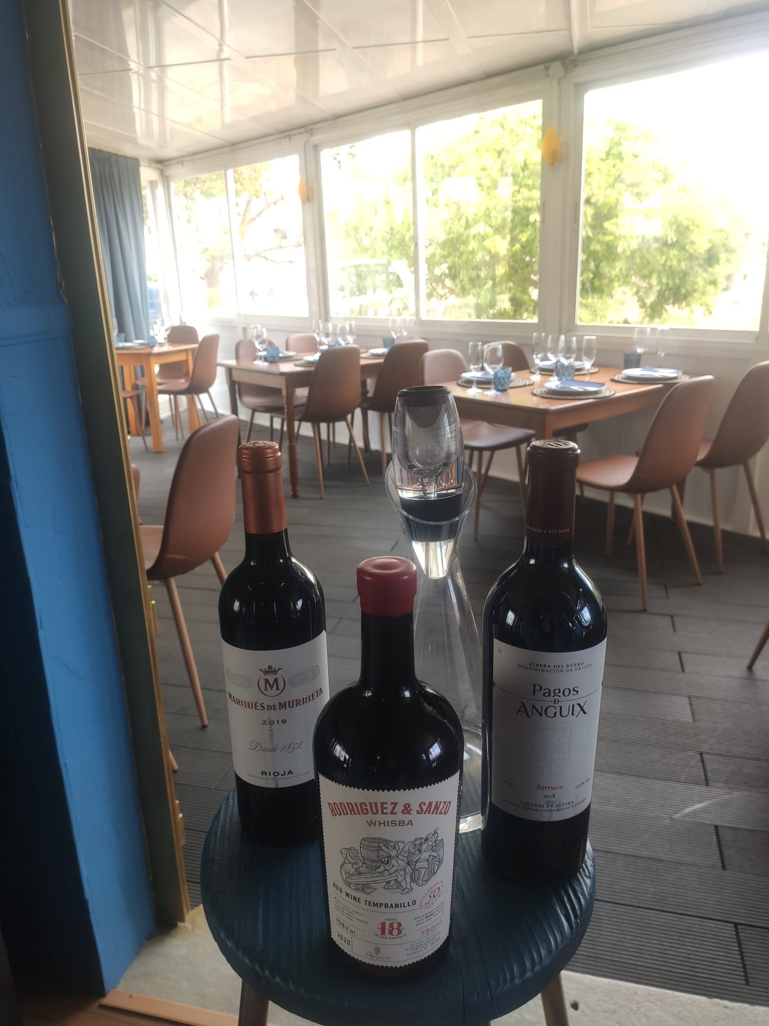 Tres botellas de vino están sentadas en una mesa en un restaurante.