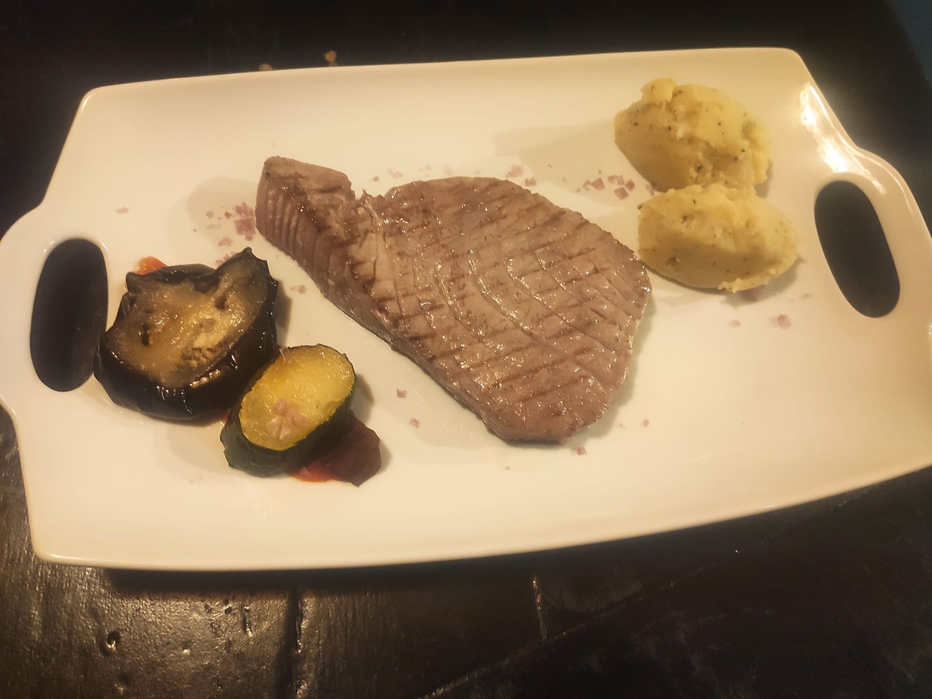 Un plato blanco con carne y verduras encima.