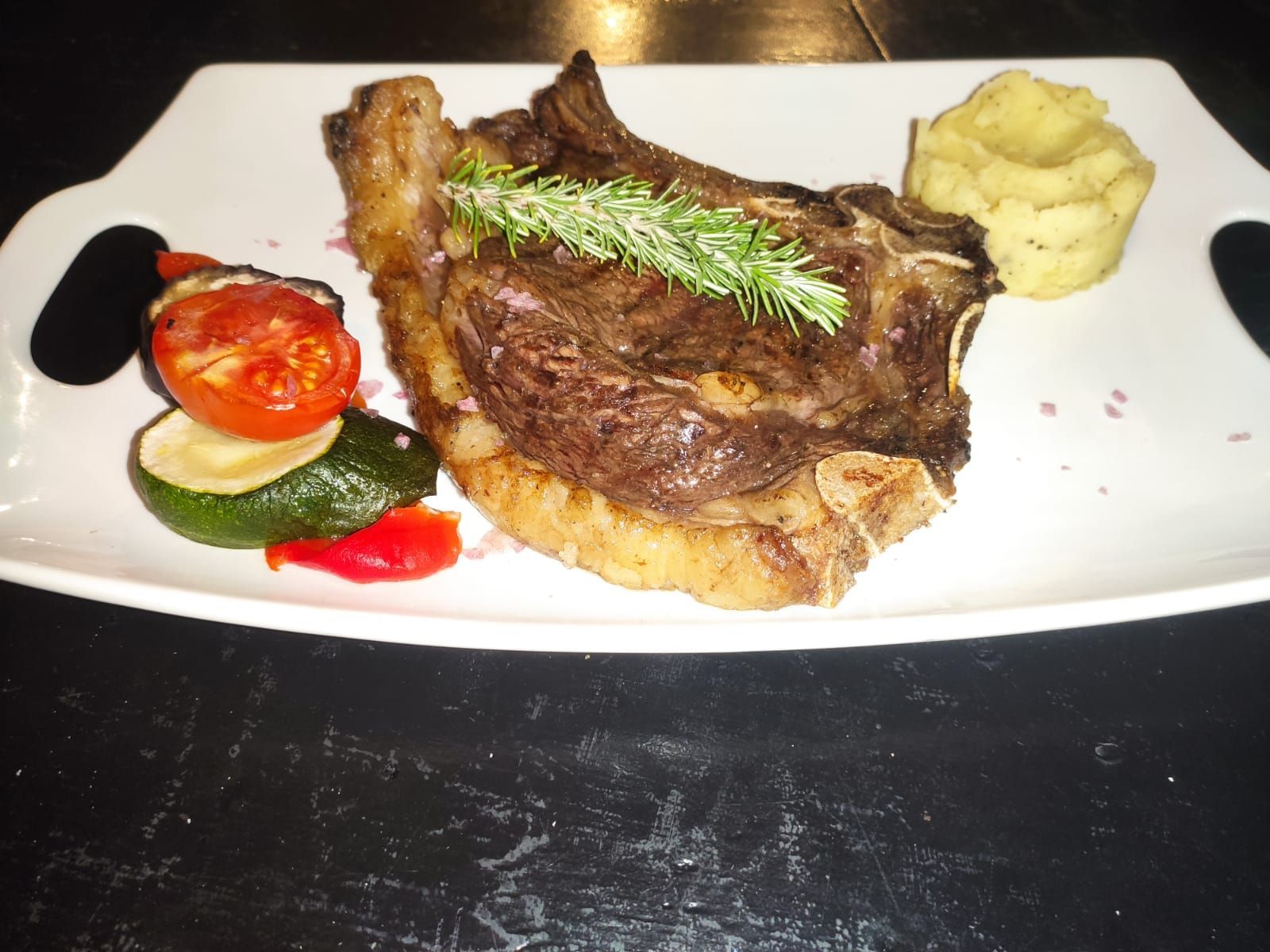 Un plato blanco con carne y verduras encima.