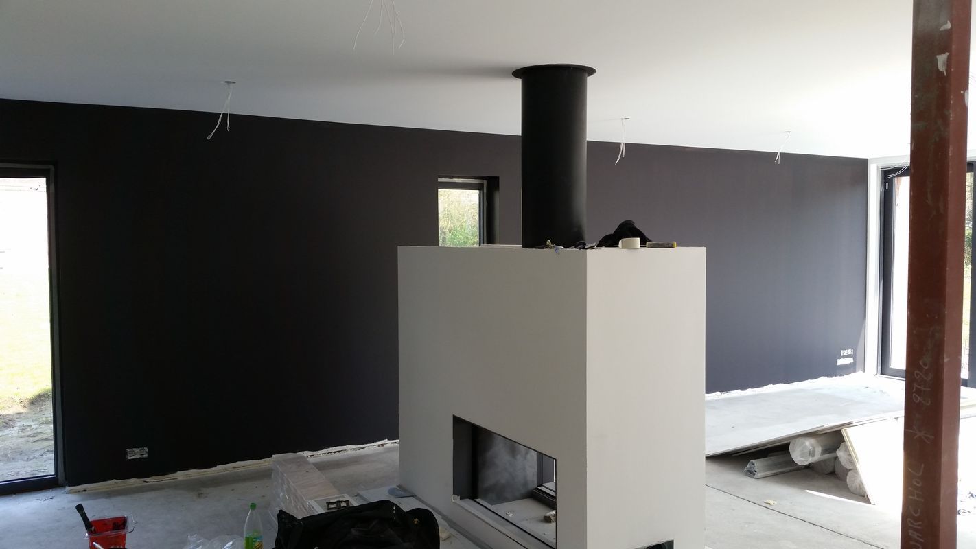 Travaux en cours de revêtements muraux et sols avec cheminée au centre