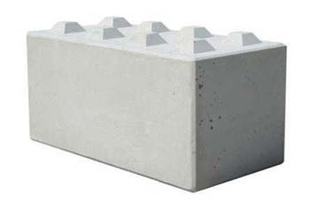 Bloc de béton gris avec des picots en relief sur le dessus, ressemblant à une grosse brique de construction.