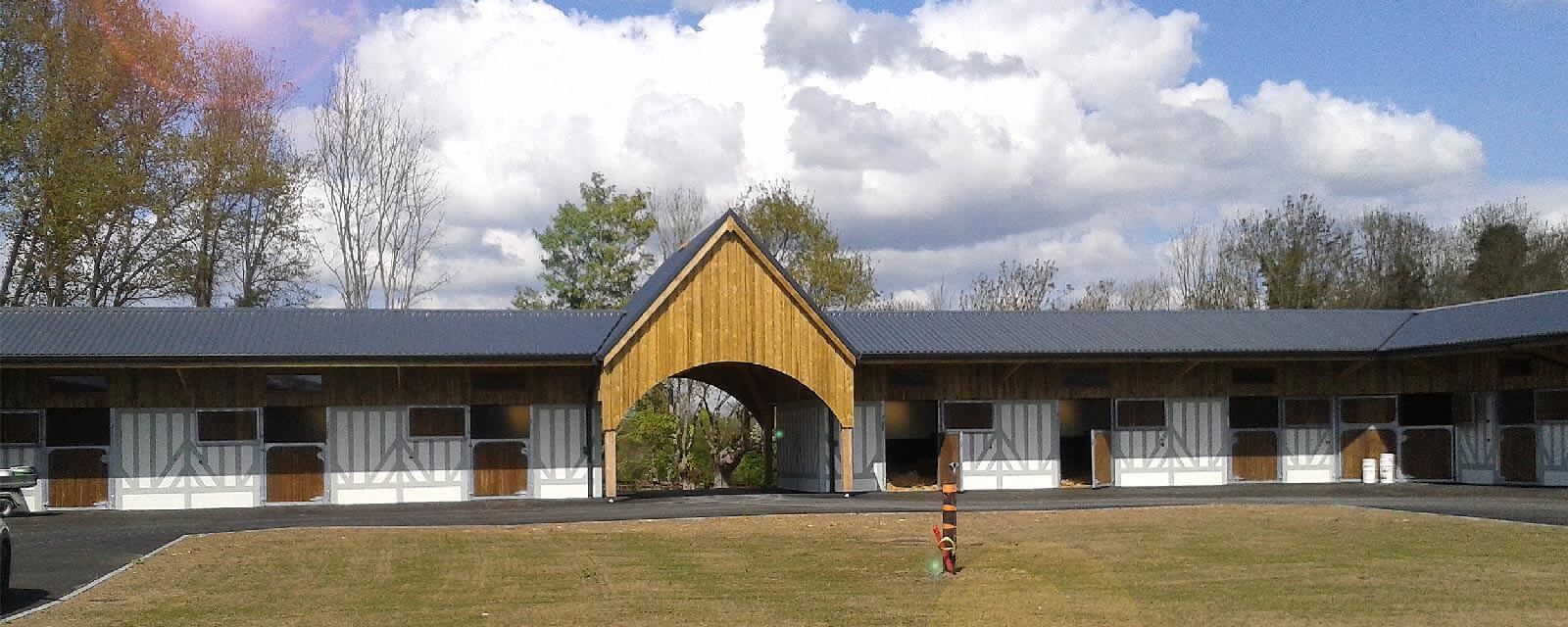 Un motel avec une arche en bois au centre. Pelouse verte, ciel bleu et arbres en arrière-plan.