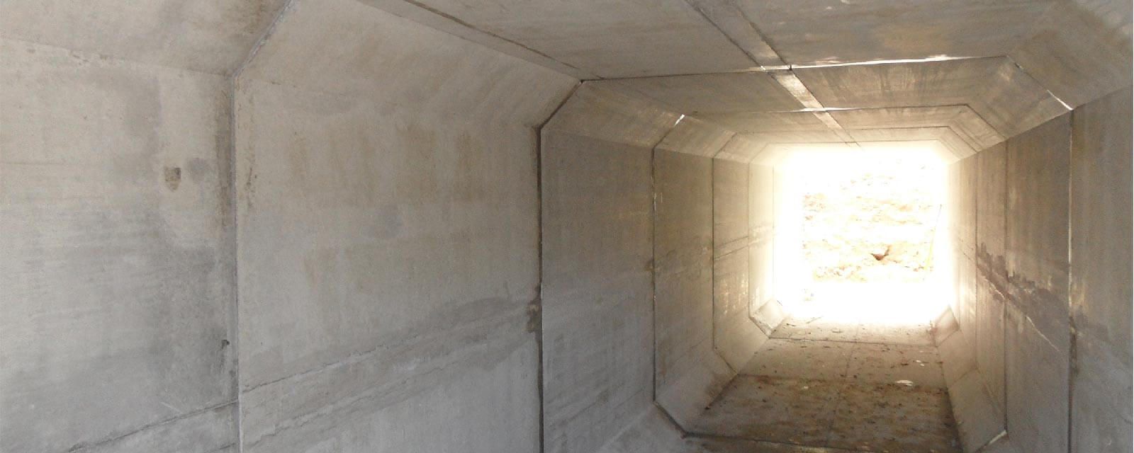 Tunnel en béton avec une lumière vive au bout.