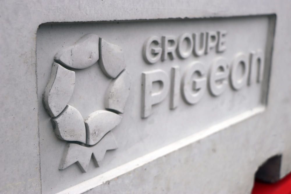 Gros plan sur une dalle de béton portant le logo « GROUPE Pigeon », une forme géométrique, et un texte en relief.