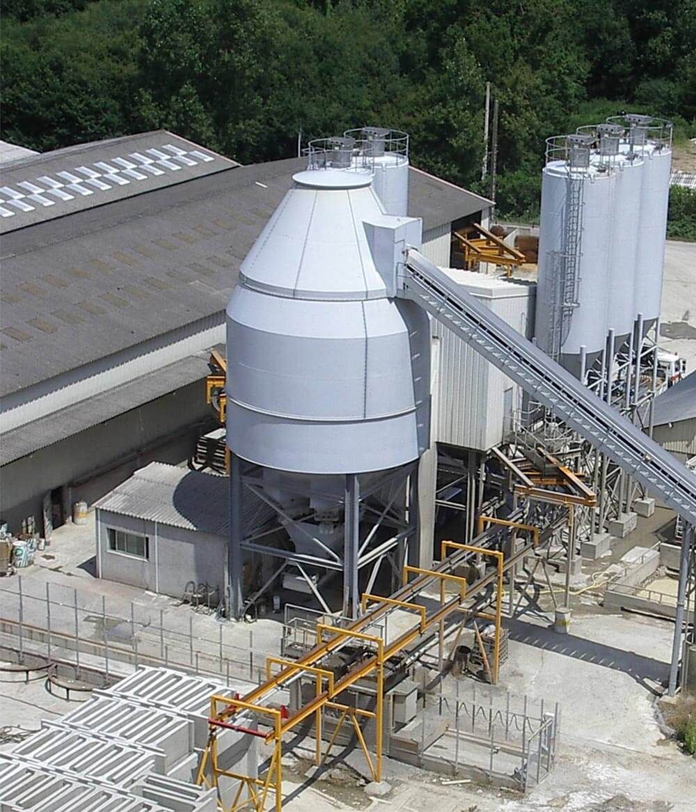 Installation industrielle avec silos, convoyeurs et pipelines ; vue extérieure.