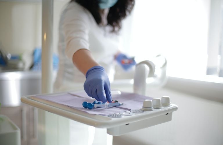 In einer Zahnarztpraxis legt ein Zahnarzt eine Zahnbürste auf ein Tablett.