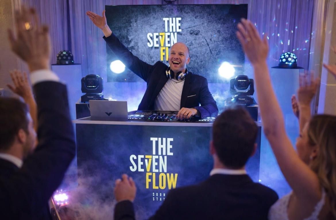 DJ con los brazos en alto, actuando en un evento, detrás de una mesa