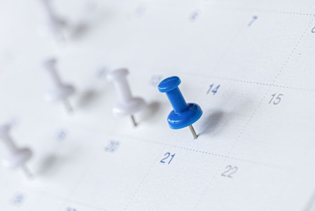 Ein offenes Buch mit einem schwarzen Lesezeichenband liegt auf einer beigen Oberfläche.