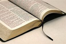 Erstkommunion Ein offenes Buch mit einem schwarzen Lesezeichenband liegt auf einer beigen Oberfläche.