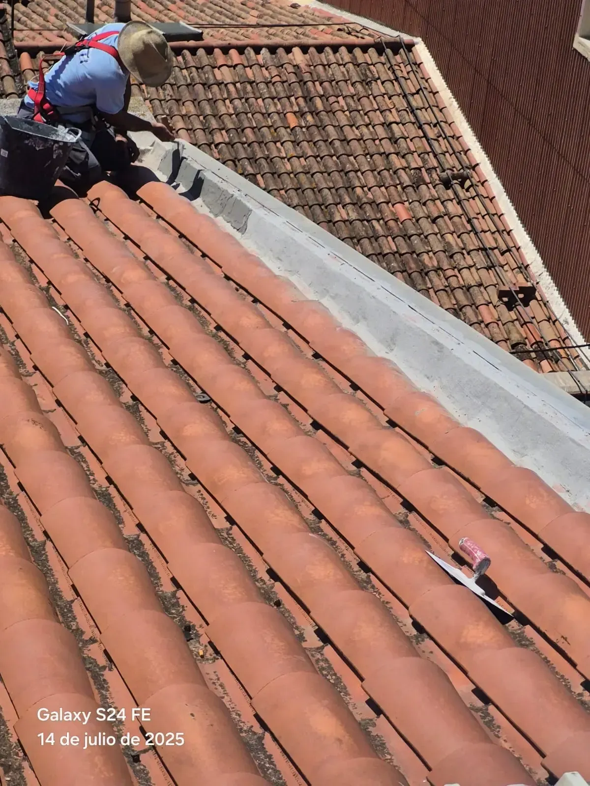 Trabajador reparando tejas de terracota en un tejado de tejas empinado