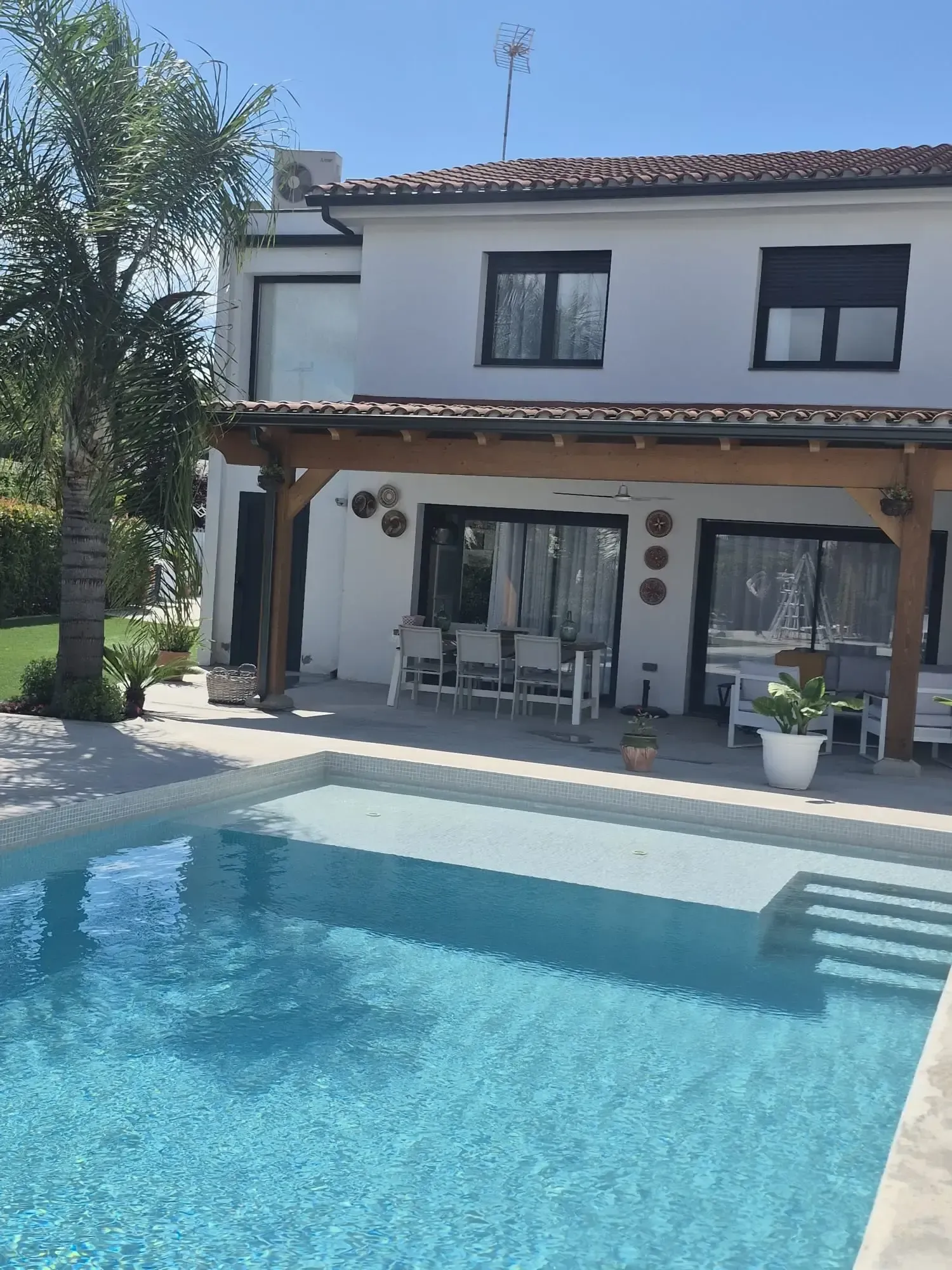 Casa moderna de dos plantas con un patio cubierto y una piscina azul en primer plano