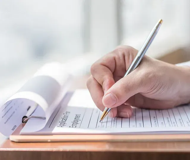 Una persona está escribiendo en un trozo de papel con un bolígrafo.