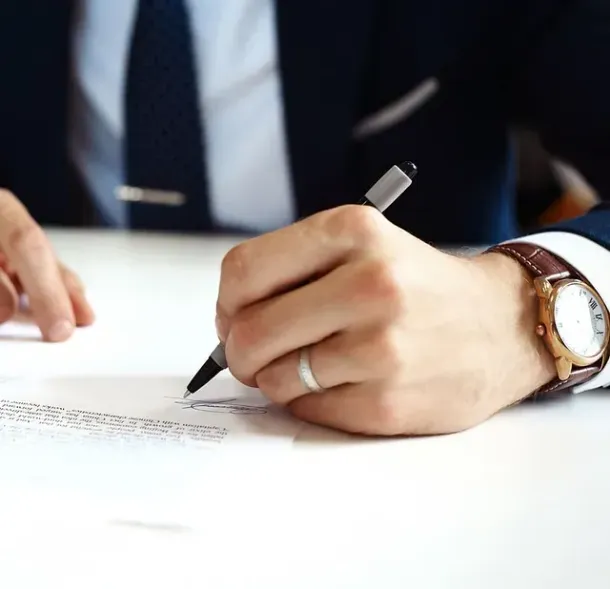 Un hombre con traje y corbata está escribiendo en un trozo de papel con un bolígrafo.