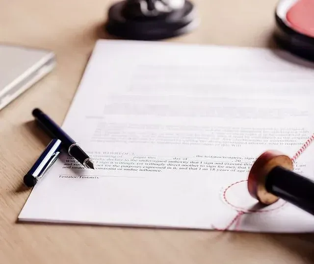 Una persona está firmando un documento con un sello y un bolígrafo.