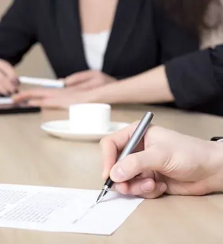 Una persona está escribiendo en un trozo de papel con un bolígrafo.