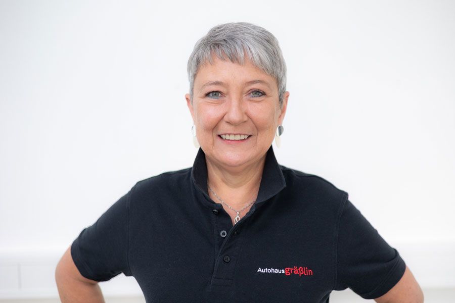 Eine Frau in einem schwarzen Poloshirt lächelt in die Kamera.