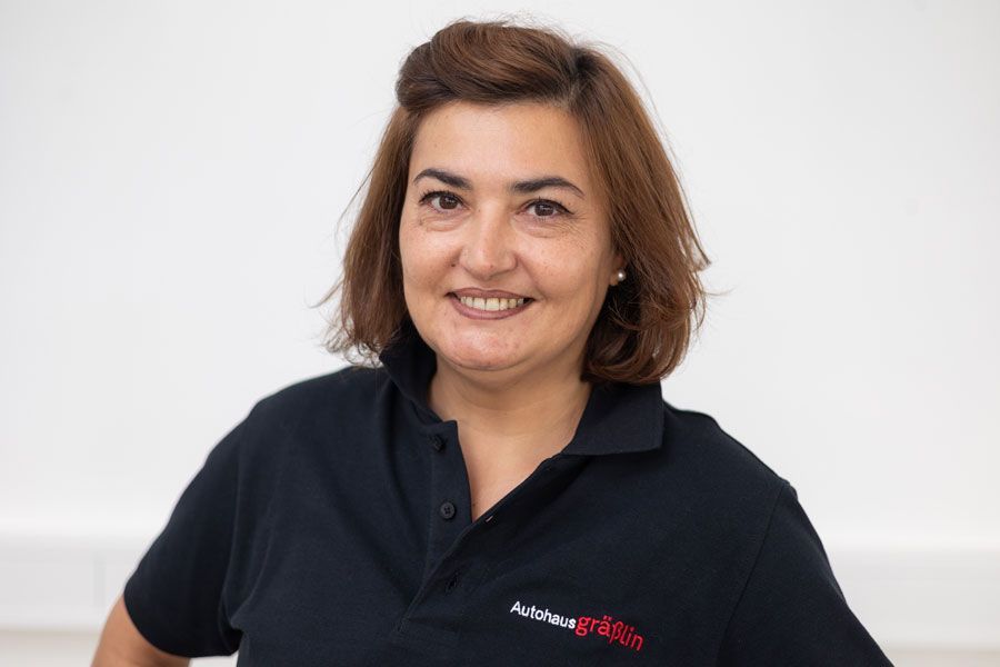 Eine Frau in einem schwarzen Poloshirt lächelt in die Kamera.
